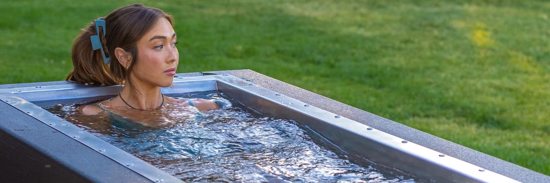 Woman relaxing in a premium cold plunge tub outdoors, showcasing high-end ice bath setup for wellness businesses