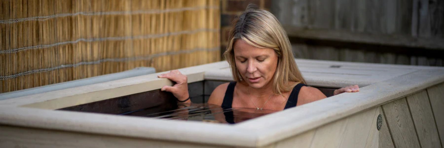 Woman entering a cold plunge tub for an ice bath therapy session designed to improve circulation, recovery, and healthy ageing.