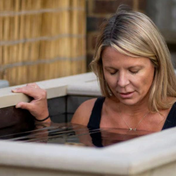 Woman entering a cold plunge tub for an ice bath therapy session designed to improve circulation, recovery, and healthy ageing.