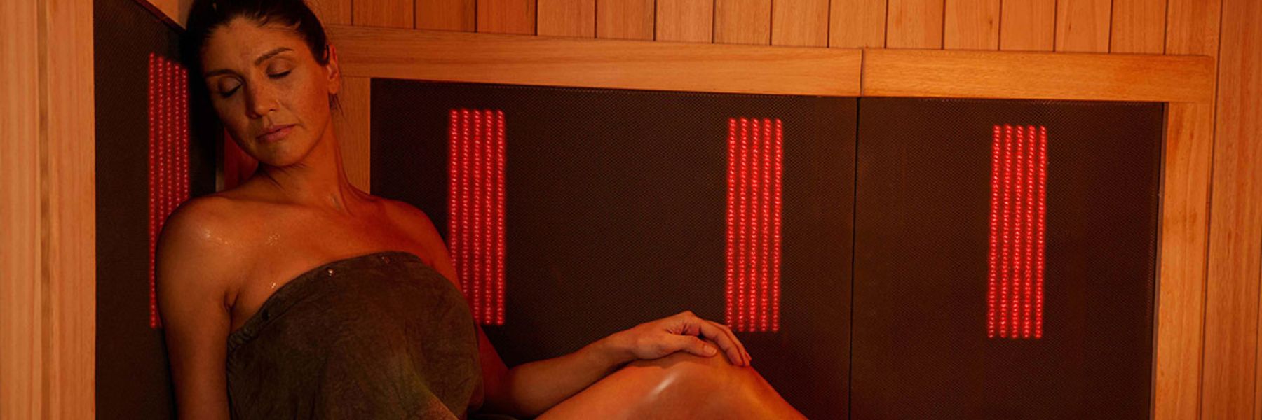 Woman relaxing in infrared sauna with red light therapy panels for skin rejuvenation and muscle recovery
