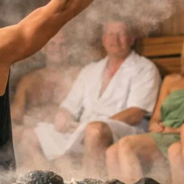 People enjoying sauna steam session with towel waving, showing heat therapy and group wellness experience