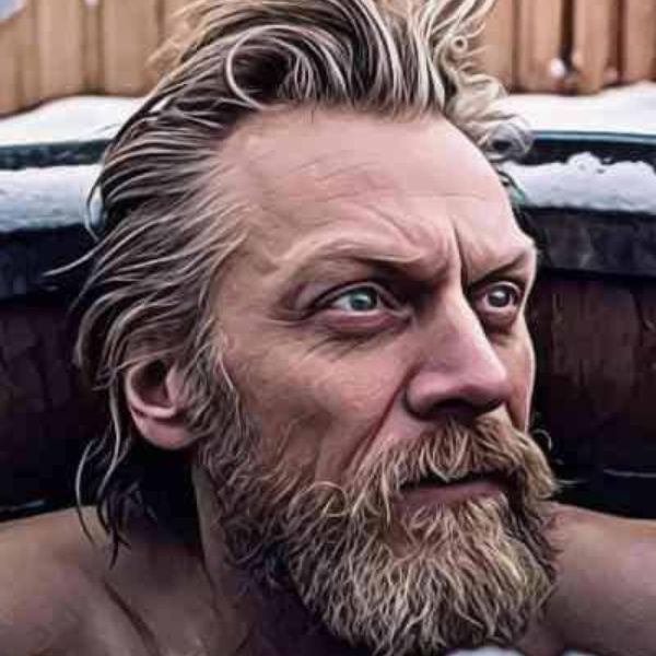Man sitting in a wooden cold plunge tub surrounded by snow, demonstrating cold water immersion in winter conditions.
