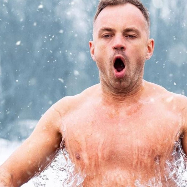 Man entering freezing lake water in winter showing the cold shock response during ice swimming.