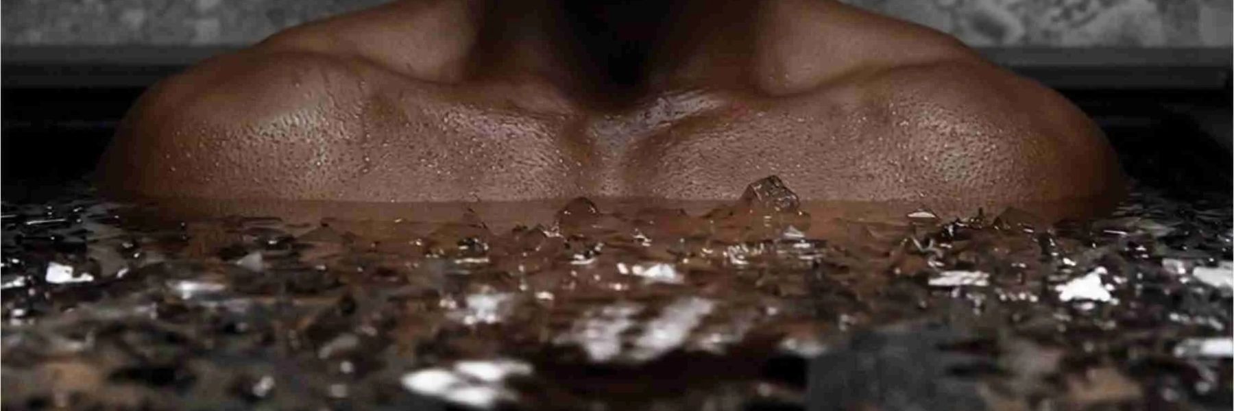 Close-up of a person’s chest submerged in an ice bath with floating ice cubes during cold plunge therapy.