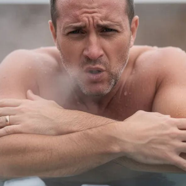 Man shivering in an ice bath, showing how cold plunge can cause temporary muscle soreness and cold shock response
