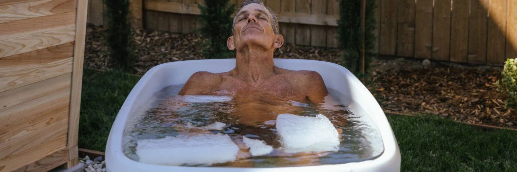 Man relaxing in an outdoor ice bath with ice, demonstrating cold plunge therapy for recovery and inflammation relief