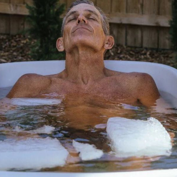 Man relaxing in an outdoor ice bath with ice, demonstrating cold plunge therapy for recovery and inflammation relief