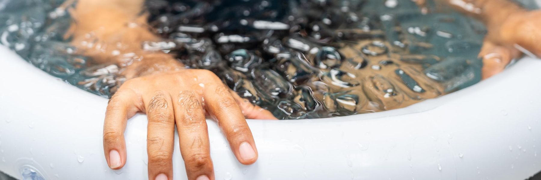 Man practices cold therapy and ice bathing in inflatable tub, using Wim Hof Method for wellness, meditation, fitness recovery, sports therapy. Wellness and healthy lifestyle.