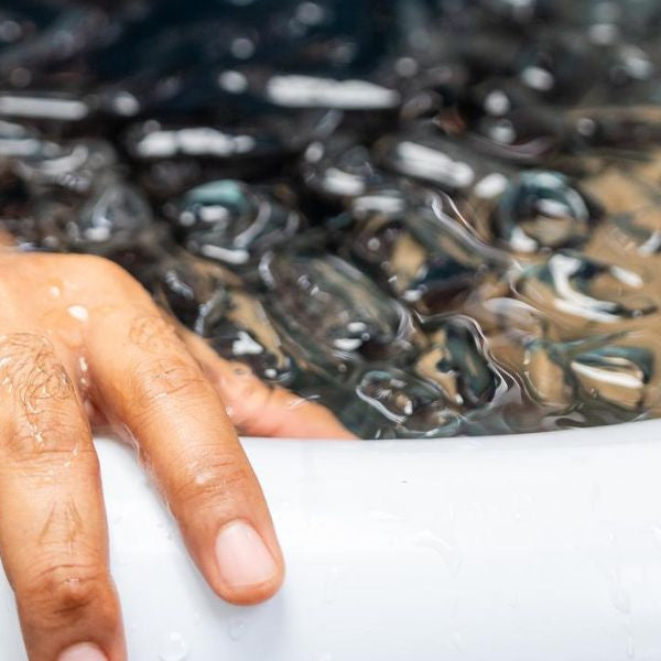 Man practices cold therapy and ice bathing in inflatable tub, using Wim Hof Method for wellness, meditation, fitness recovery, sports therapy. Wellness and healthy lifestyle.