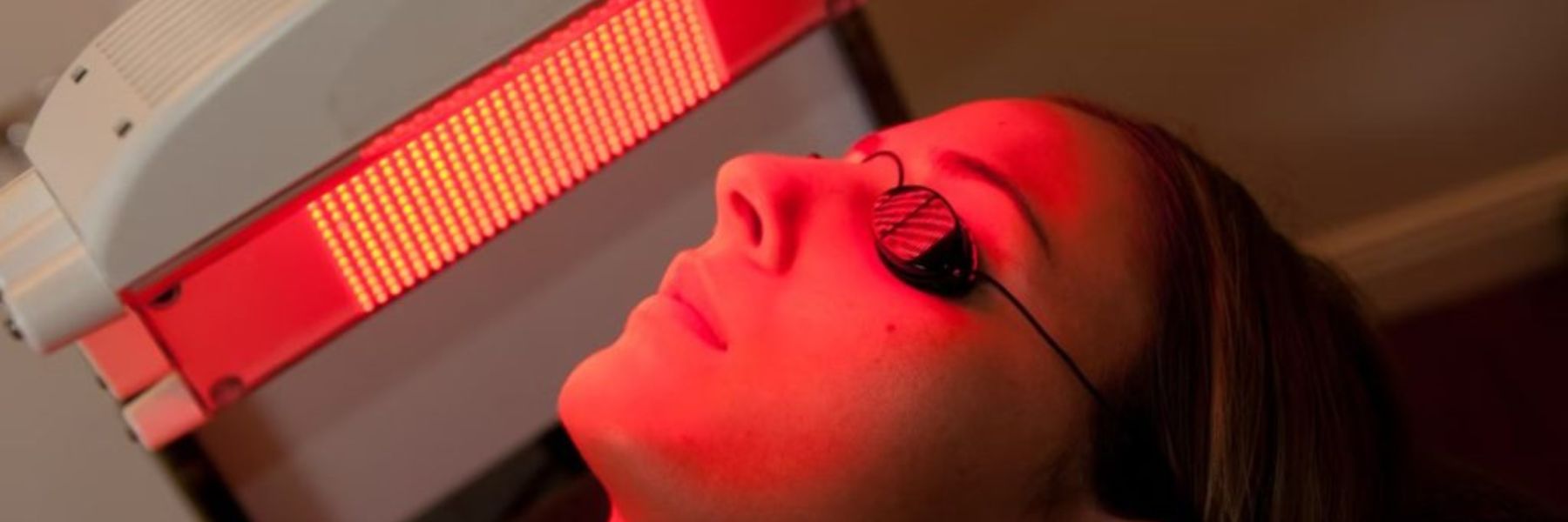 Woman wearing protective goggles during red light therapy session, ensuring safe eye protection