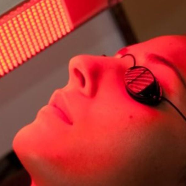 Woman wearing protective goggles during red light therapy session, ensuring safe eye protection