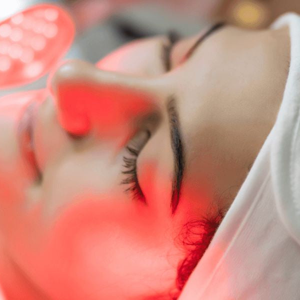 Woman receiving red light therapy facial treatment, highlighting potential effects on skin conditions like melasma