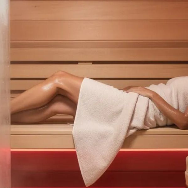 Woman relaxing in infrared sauna, supporting recovery and wellness alongside red light therapy treatments