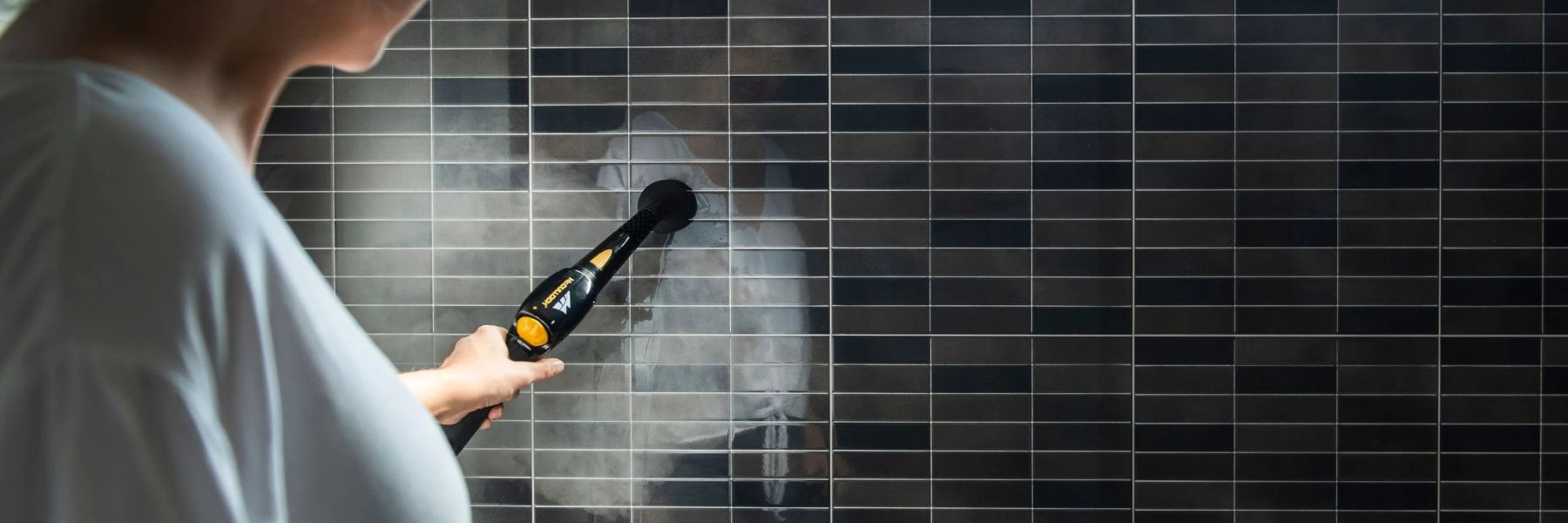 Using a steam cleaner to remove mould buildup from bathroom tiles and grout