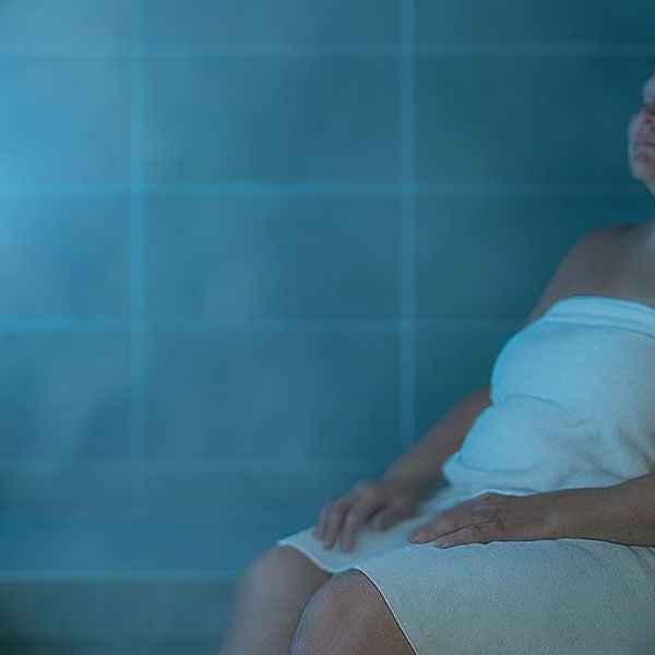 Woman sitting in steam shower surrounded by dense steam highlighting high humidity environment