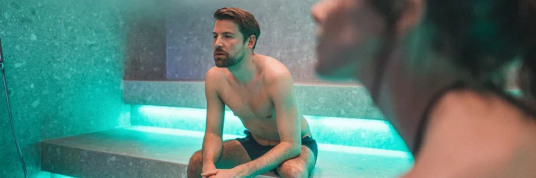Man sitting in steam room with heavy steam highlighting heat and humidity levels
