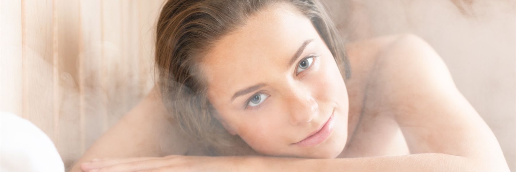 Woman relaxing in steam room with glowing skin highlighting potential acne-clearing benefits
