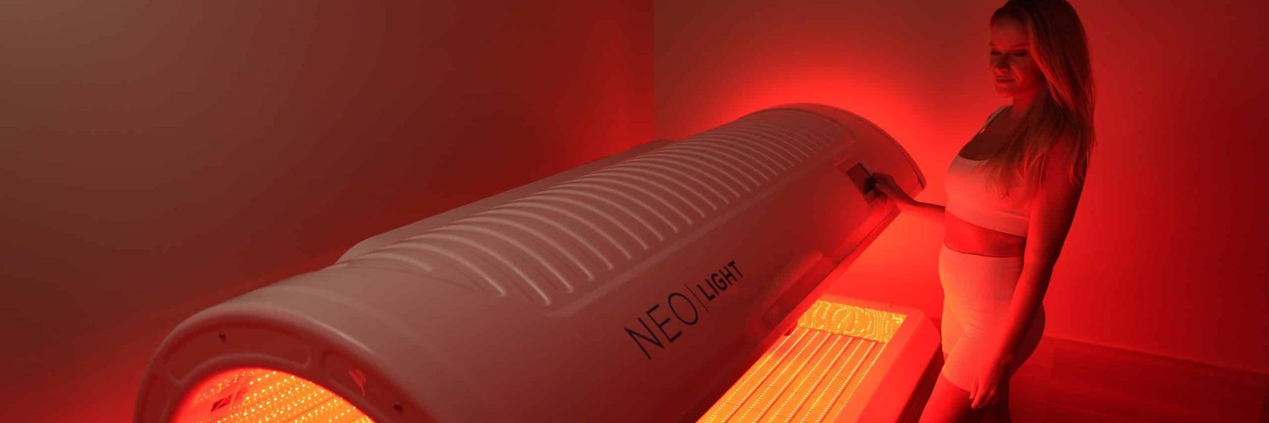 Woman using a red light therapy bed, showing full-body photobiomodulation for skin and recovery benefits