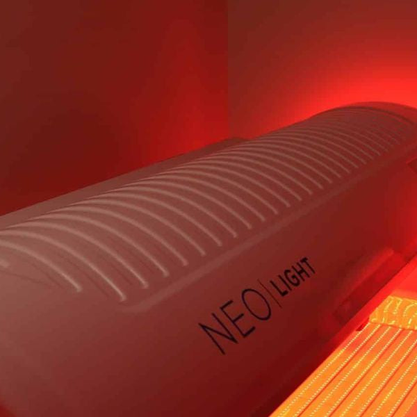 Woman using a red light therapy bed, showing full-body photobiomodulation for skin and recovery benefits