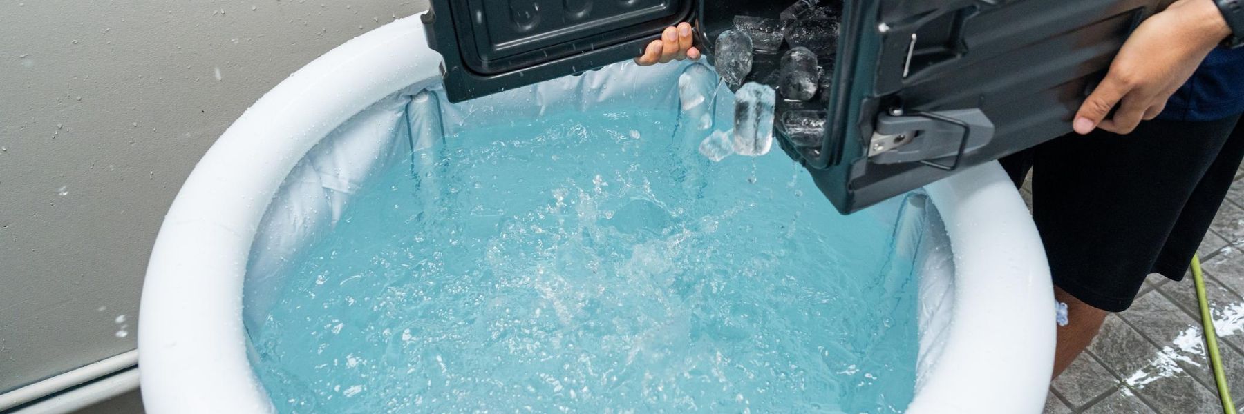 Cold plunge tub filled with ice cubes and water prepared for an outdoor ice bath recovery session.