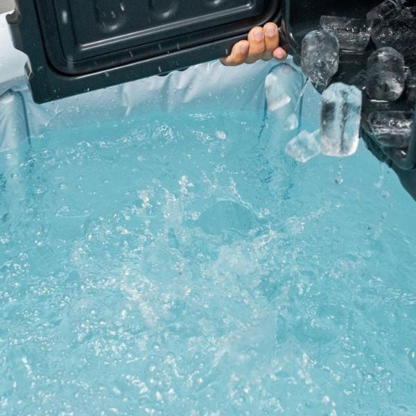 Cold plunge tub filled with ice cubes and water prepared for an outdoor ice bath recovery session.