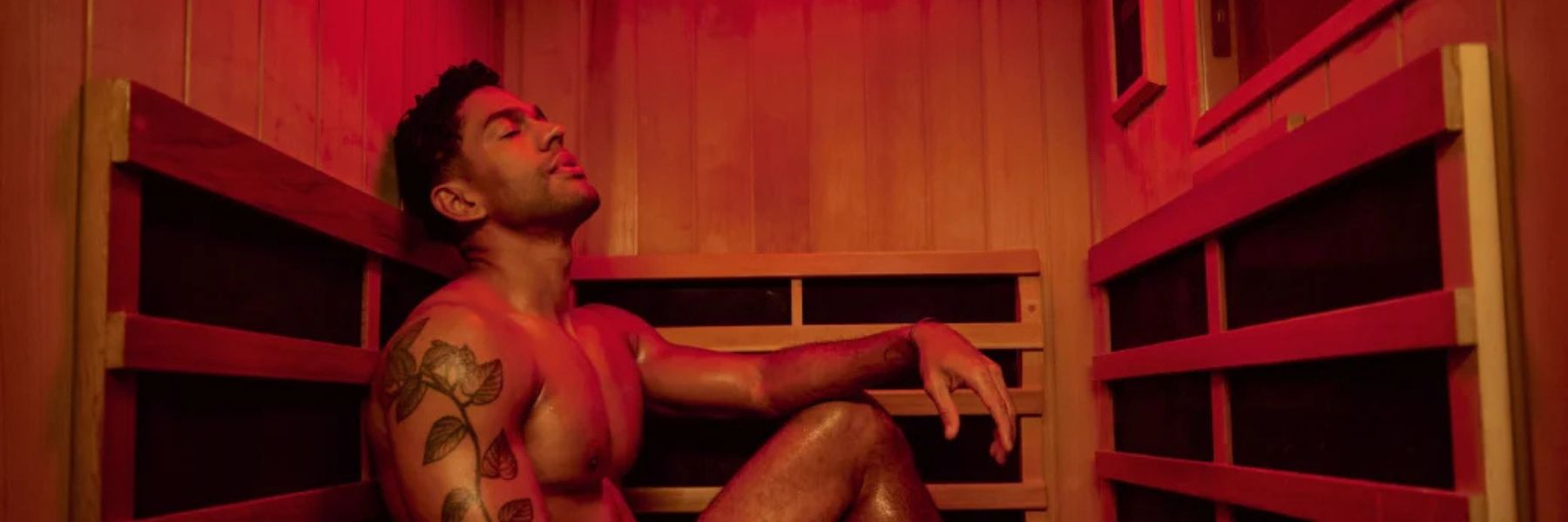 Man with tattoo sitting in infrared sauna with red light therapy, exploring effects on tattooed skin