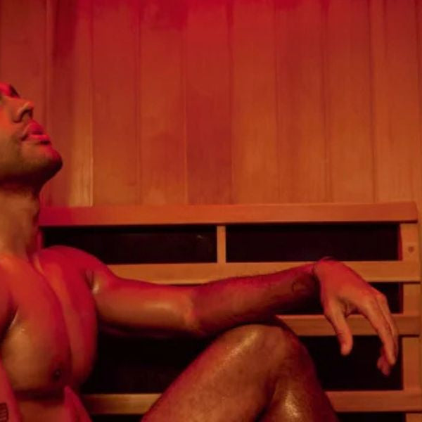 Man with tattoo sitting in infrared sauna with red light therapy, exploring effects on tattooed skin