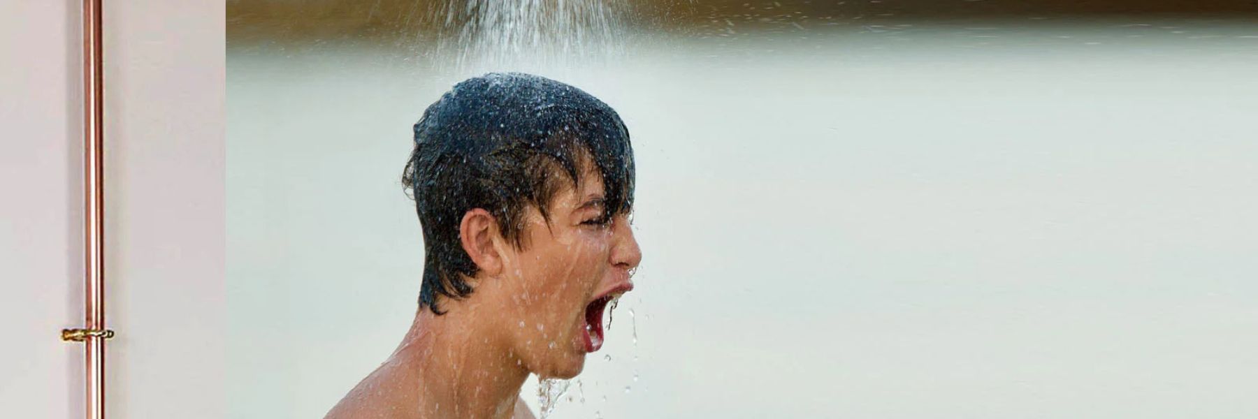 Practising controlled breathing while standing under a cold shower during a cold plunge routine.