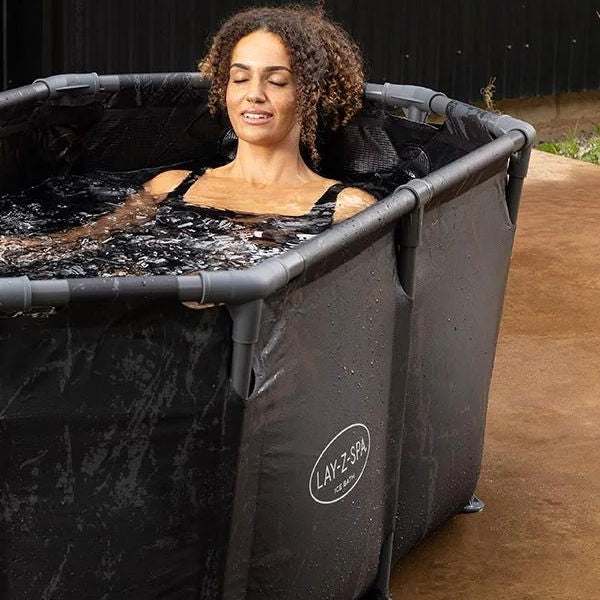 Preparing a cold plunge ice bath tub in a bathroom using bags of ice.