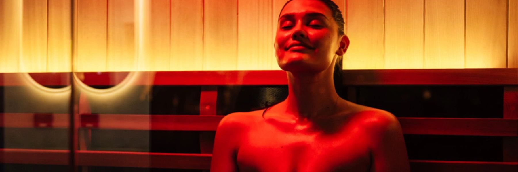 Woman in infrared sauna with red light therapy, supporting lymphatic drainage and detoxification