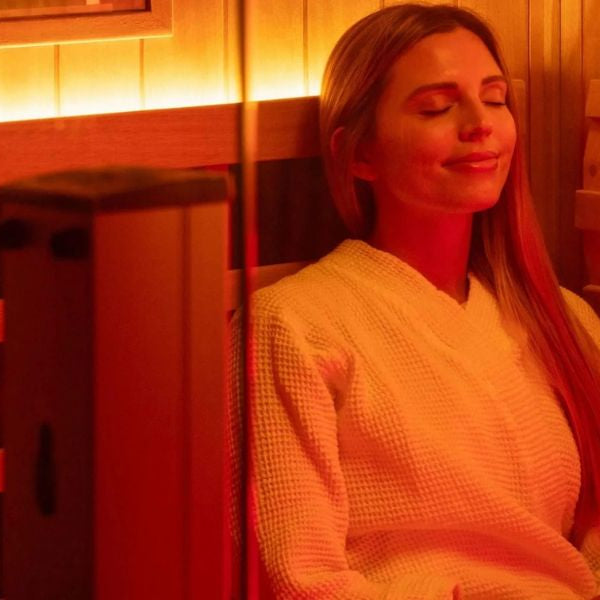 Woman relaxing in infrared sauna with red light therapy, promoting circulation and blood pressure benefits