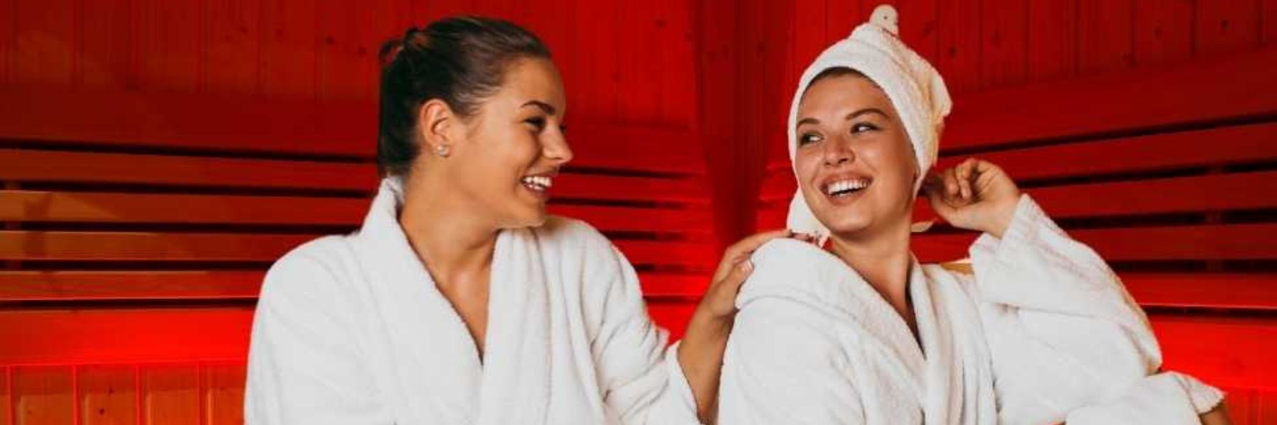 Two women relaxing in infrared sauna, promoting social wellbeing and mental health benefits
