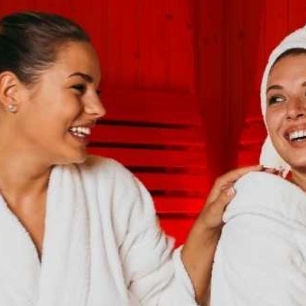 Two women relaxing in infrared sauna, promoting social wellbeing and mental health benefits