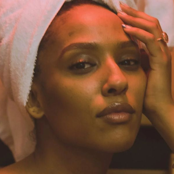 Woman with towel in sauna with warm light, illustrating skin detox, hydration, and glow-enhancing benefits