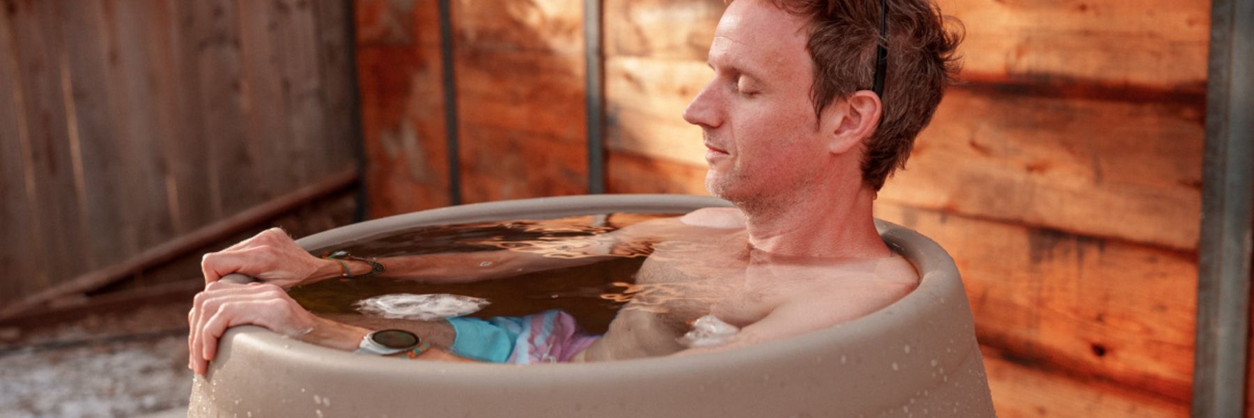 Person using a modern cold plunge tub outdoors as part of a cold water immersion therapy routine.