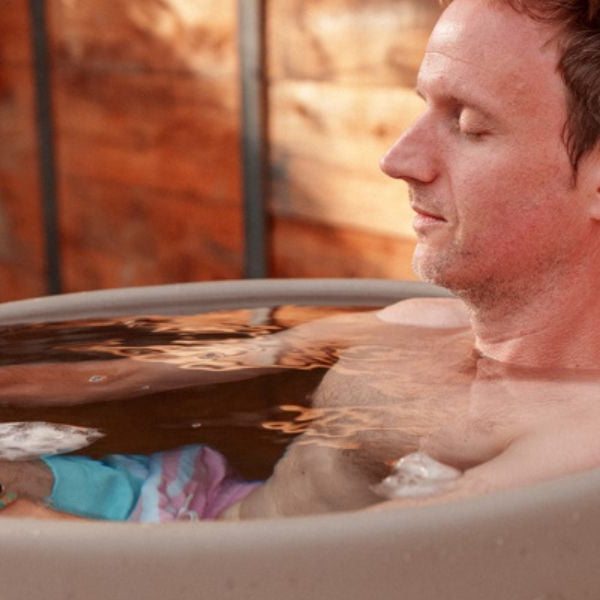 Person using a modern cold plunge tub outdoors as part of a cold water immersion therapy routine.