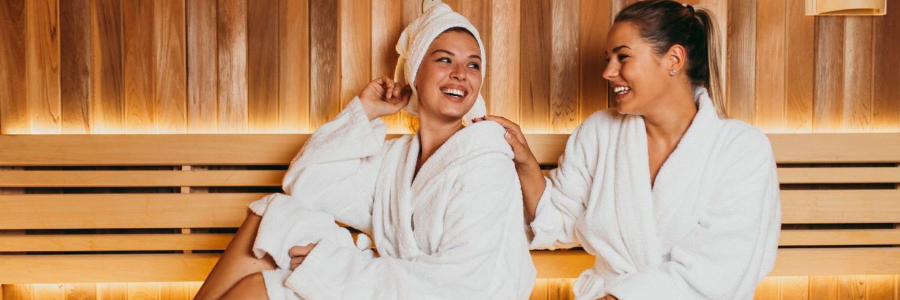 Two women relaxing in sauna together, highlighting social wellness, stress relief, and relaxation benefits