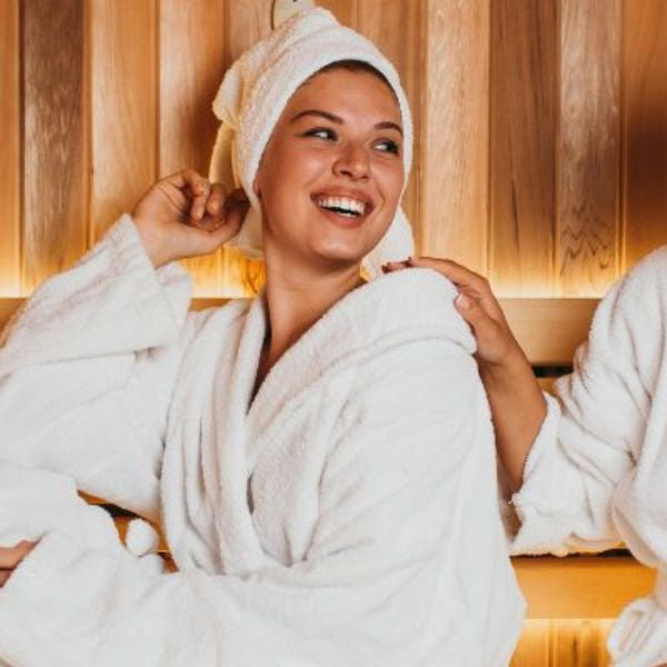 Two women relaxing in sauna together, highlighting social wellness, stress relief, and relaxation benefits