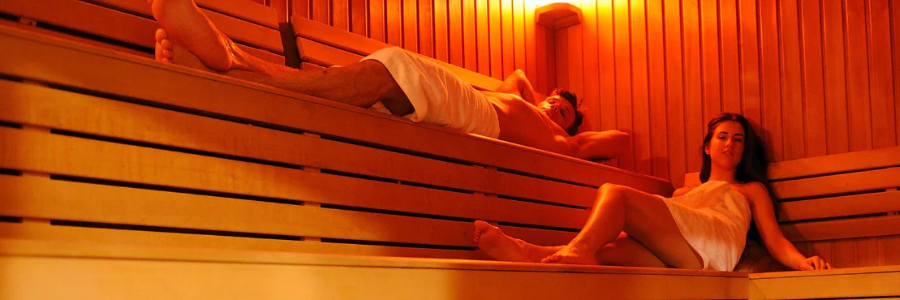 Couple relaxing in traditional sauna, supporting detox, circulation, and weight loss alongside red light therapy