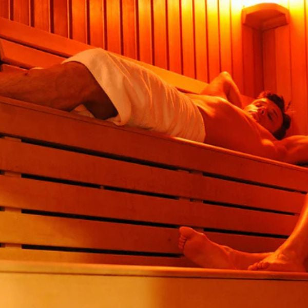 Couple relaxing in traditional sauna, supporting detox, circulation, and weight loss alongside red light therapy