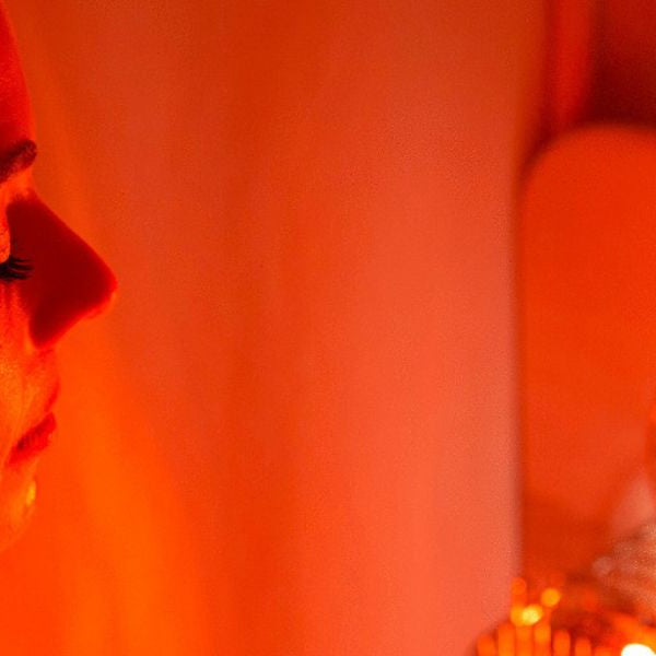 Woman using red light therapy lamp for facial treatment, supporting skin healing and collagen production