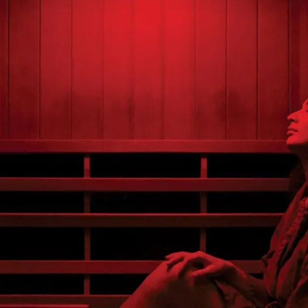 Woman relaxing in infrared sauna with red light therapy, supporting overall wellness and recovery