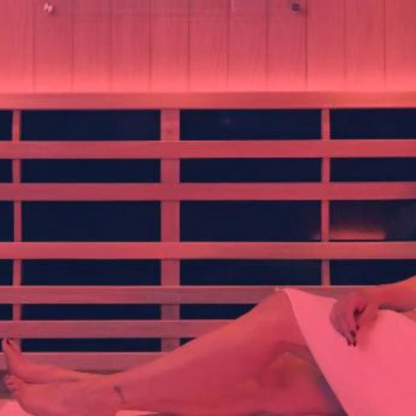 Woman relaxing in infrared sauna with red light therapy to support cellular repair and overall wellness