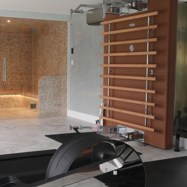 Modern home gym with steam room in the background, showing integrated wellness and fitness space