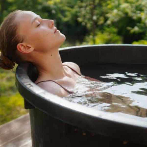 Person slowly entering a cold plunge tub while practising controlled breathing during cold exposure.
