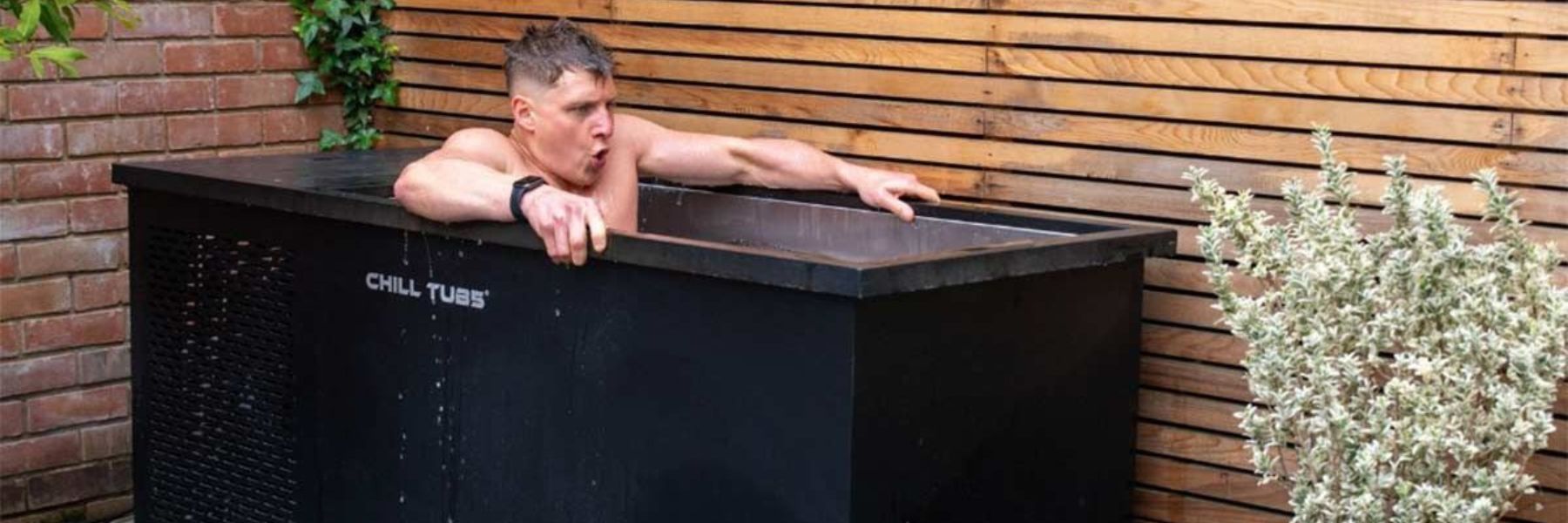 Runner recovering after a long run by sitting in a cold plunge tub outdoors for ice bath recovery therapy.