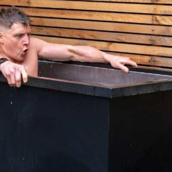 Runner recovering after a long run by sitting in a cold plunge tub outdoors for ice bath recovery therapy.