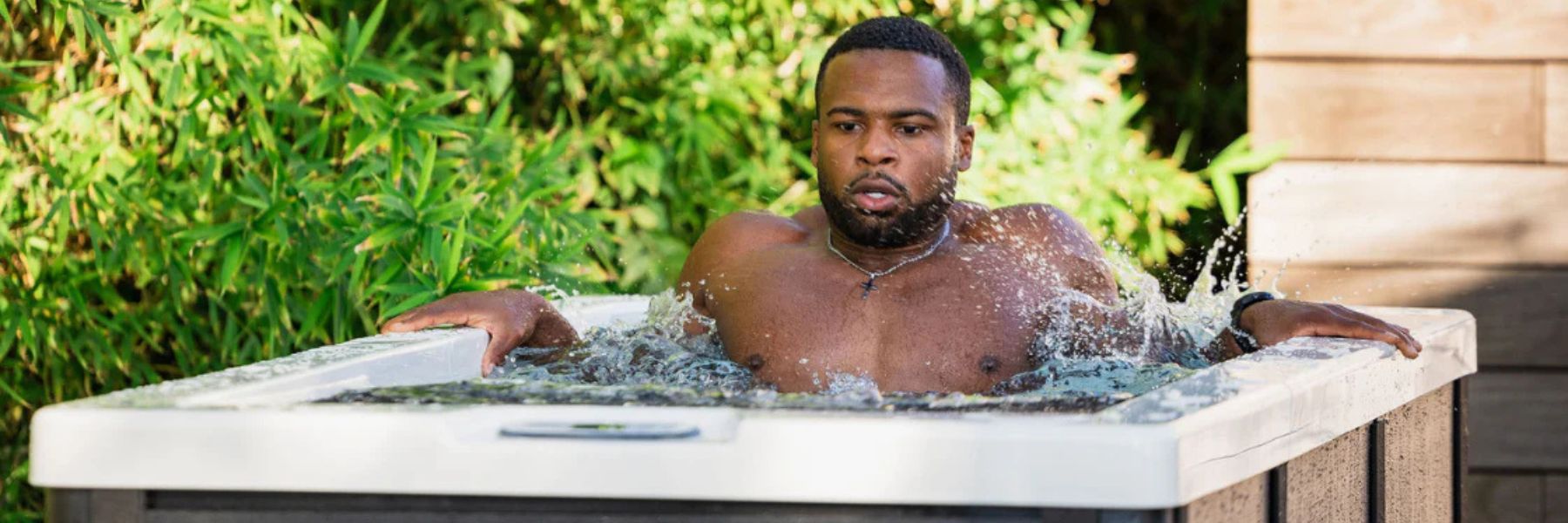 Athlete sitting in a cold plunge tub filled with ice after a strength training workout to support muscle recovery.