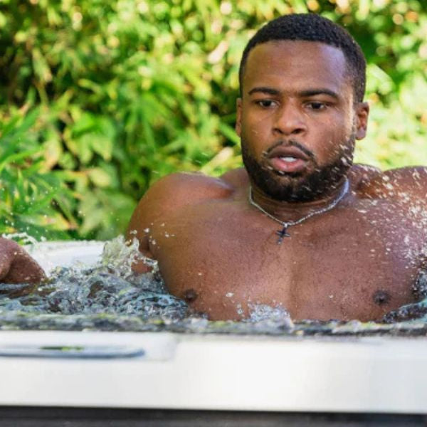 Athlete sitting in a cold plunge tub filled with ice after a strength training workout to support muscle recovery.