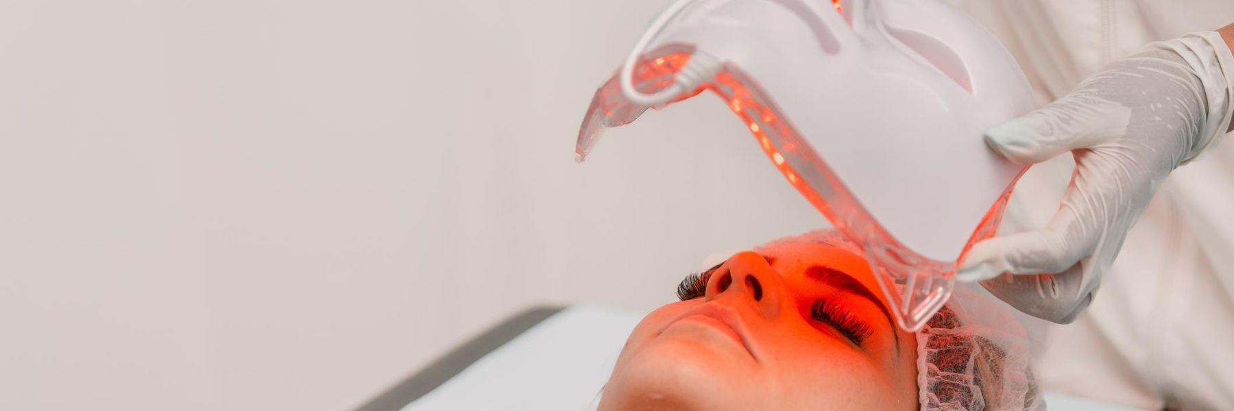 Clinician performing red light therapy facial treatment using handheld device for skin rejuvenation